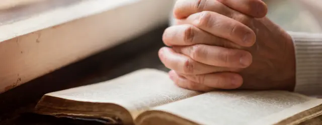 Hands folded over bible